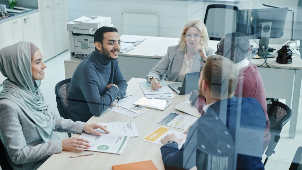 Colleagues from diverse backgrounds smiling and talking around a meeting table